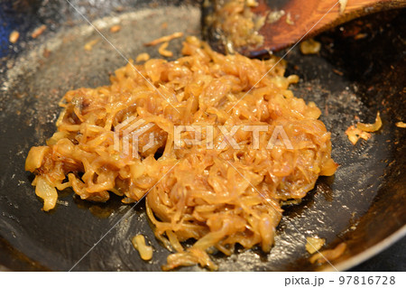 鉄のフライパンで飴色になるまで玉葱を炒める 97816728