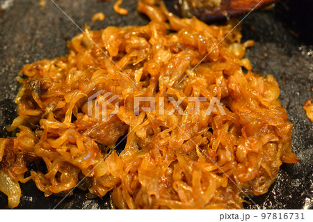 鉄のフライパンで飴色になるまで玉葱を炒める 97816731