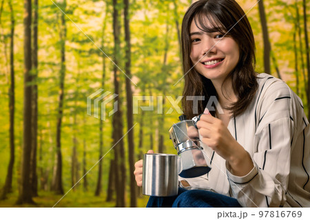 グランピング　キャンプ場でコーヒーを用意する若い女性 97816769
