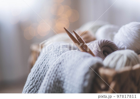 Cozy homely atmosphere. Female hobby knitting. Yarn in neutral shades in a basket Cozy homely atmosphere. Female hobby knitting. Yarn in neutral shades in a basket 97817811