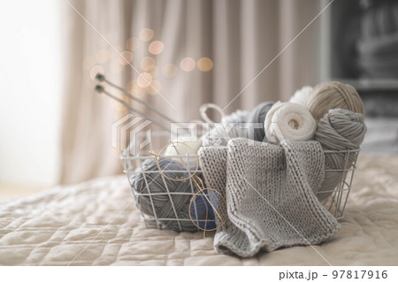 Cozy homely atmosphere. Female hobby knitting. Yarn in neutral colors in a black iron black basket. Cozy homely atmosphere. Female hobby knitting. Yarn in neutral colors in a black iron black basket. 97817916