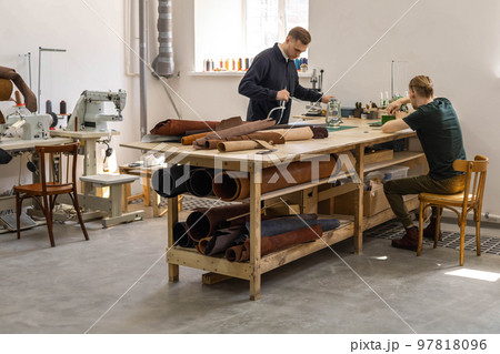 Craftsman unwrapping bundle of stuff natural material working at leather workshop. Leatherwork 97818096