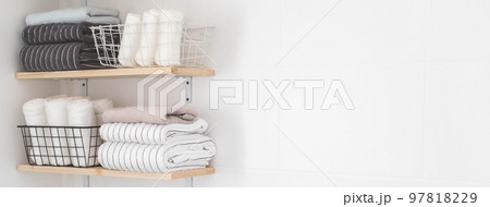 Towels roll neatly folded metallic basket arrangement wooden shelves minimal bathroom interior Towels roll neatly folded metallic basket arrangement wooden shelves minimal bathroom interior 97818229