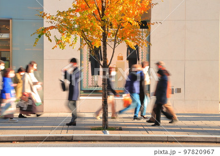 都会の晩秋　街路樹の横の歩道を過ぎる人々 97820967
