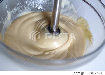 Defocus beating of homemade mayonnaise with olive oil. Mix ingredients for sauce. The chef uses a blender. Glass bowl. Closeup. Out of focus Defocus beating of homemade mayonnaise with olive oil. Mix ingredients for sauce. The chef uses a blender. Glass bowl. Closeup. Out of focus 97822424