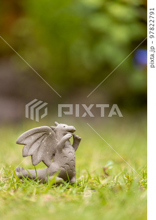 芝生の上に置いてある可愛い素焼のドラゴンの置物 97822791