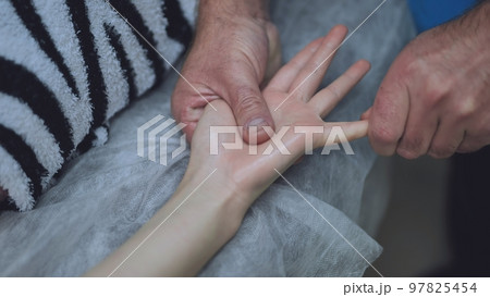 A masseur massages the wrists of a girl. 97825454