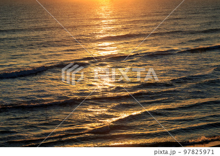 日の出の反射で黄金色に染まる海原 97825971