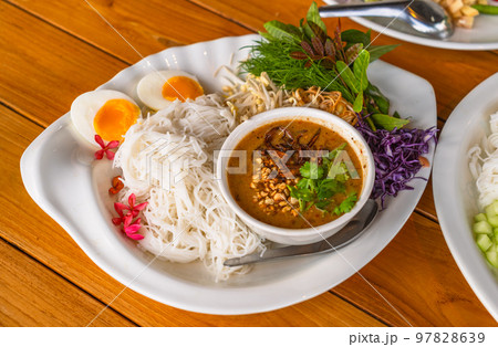 Thai vermicelli or rice noodles with peanut sauce curry, side dish with organic vegetables and boiled egg. Thai vermicelli or Thai rice noodle with curry is called Ka Nom Jean in the Thai language. 97828639