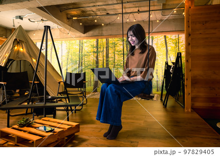 ワーケーション　ブランコに座ってノートパソコンを操作する若い女性 97829405
