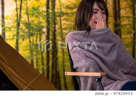 寒くてブランケットに包まる若い女性　キャンプイメージ 97829453