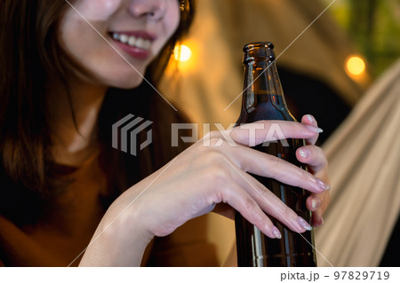キャンプでビールを片手に微笑む若い女性のイメージカット キャンプでビールを片手に微笑む若い女性のイメージカット 97829719