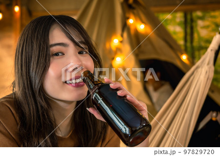 キャンプでビールを片手に微笑む若い女性 キャンプでビールを片手に微笑む若い女性 97829720