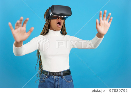 Shocked african woman wearing virtual reality goggles Shocked african woman wearing virtual reality goggles 97829792