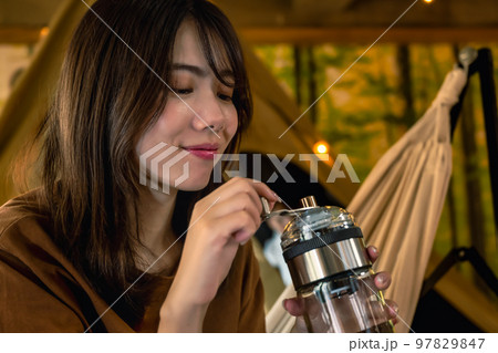 グランピング　キャンプ場で朝のコーヒーを準備する若い女性 97829847