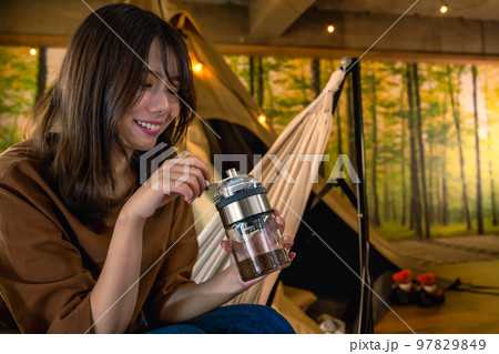 グランピング　キャンプ場で朝のコーヒーを準備する若い女性 97829849
