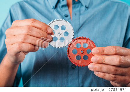 Woman fits two gears as concept of teamwork, partnership, integration Woman fits two gears as concept of teamwork, partnership, integration 97834974
