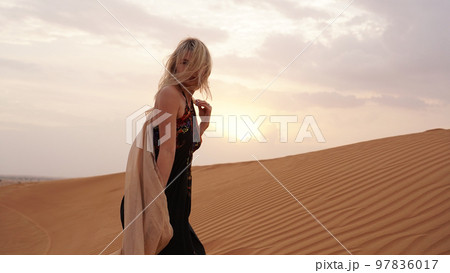 Woman in dress with view of desert sand in sunset light. Landscape Woman in dress with view of desert sand in sunset light. Landscape 97836017