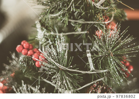 Christmas tree artificial decorative plastic green shiny sequins sprinkles, LED garland light, red berry ball rowan tassels. Winter holiday leisure. Vintage wash matte effect tone 97836802