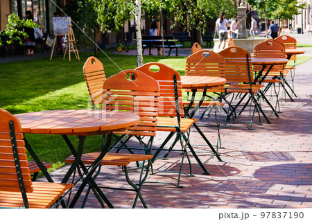 Chairs and tables in garden restaurant with table legs and chair legs made of iron and wooden tops Chairs and tables in garden restaurant with table legs and chair legs made of iron and wooden tops 97837190