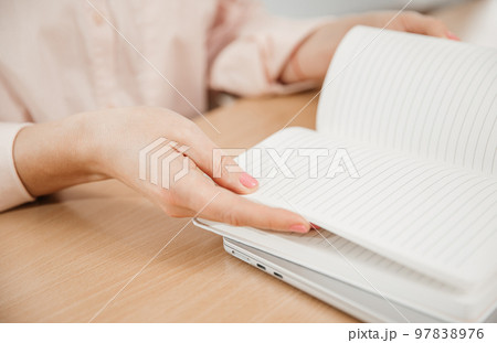 Close-up of woman's hands at work, she write the plan of the day in a notebook at her workplace. Work, learning, student and home office concept Close-up of woman's hands at work, she write the plan of the day in a notebook at her workplace. Work, learning, student and home office concept 97838976