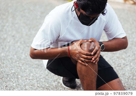 Close up Asian young sport runner black man wear watch sitting hands joint hold knee pain during the run while running at the outdoor street health park, healthy exercise injury from workout concept Close up Asian young sport runner black man wear watch sitting hands joint hold knee pain during the run while running at the outdoor street health park, healthy exercise injury from workout concept 97839079