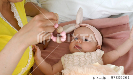 Young mother shaking wooden rattle toy while playing with her baby at home Young mother shaking wooden rattle toy while playing with her baby at home 97839261