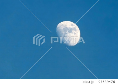 The moon rises in the daytime on the blue sky. The moon rises in the daytime on the blue sky. 97839476