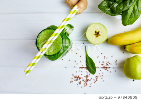 From above view of jar mug filled with green smoothie and ingredients on wooden table. Healthy food  97840909