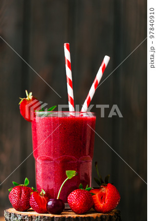 Ftont view of berry juice or smoothie with fresh strawberries and cherries on wooden background. 97840910