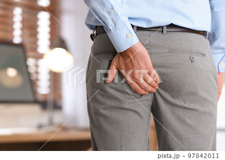 Man suffering from hemorrhoid in office, closeup 97842011