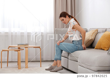Young woman suffering from hemorrhoid on sofa at home 97842025