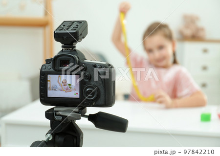 Cute little blogger with slime recording video at home, focus on camera 97842210