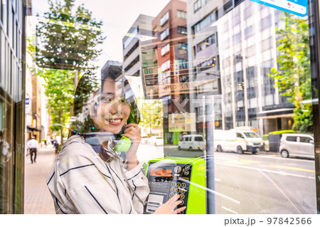 携帯電話の通信障害で公衆電話を使う若い女性 97842566