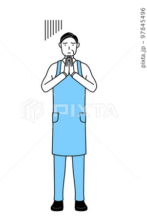 体の前で手を合わせて謝るエプロンを着たシニア男性 97845496