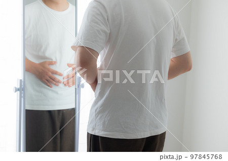 お腹を気にする若い男性 97845768