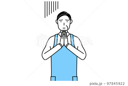 体の前で手を合わせて謝るエプロンを着たシニア男性 97845922