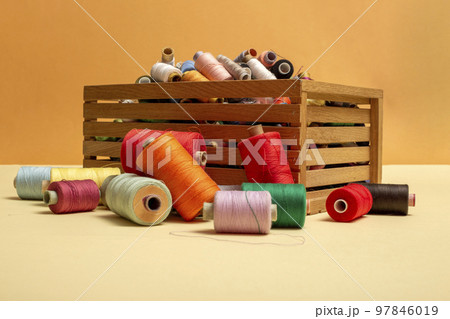 A box with multi colored coins of different threads on a colored background A box with multi colored coins of different threads on a colored background 97846019