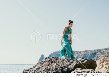 Side view a Young beautiful sensual woman with black hair in a long mint dress posing on a beach with calm sea bokeh lights on sunny day. Girl on the nature on blue sky background. Fashion photo Side view a Young beautiful sensual woman with black hair in a long mint dress posing on a beach with calm sea bokeh lights on sunny day. Girl on the nature on blue sky background. Fashion photo 97846675