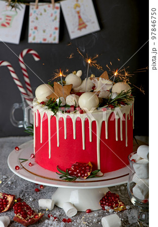 Festive Christmas cake on a rustic wooden stand and holiday decoration. New Year cards and sparklers 97846750