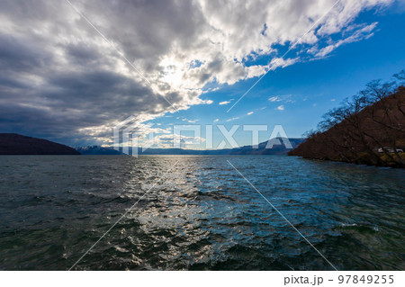 春の青森県・十和田湖で見た、湖岸沿いの風景と夕暮れが迫る空 97849255