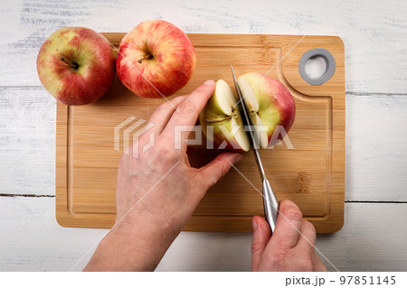 Slicing an apple on a bamboo cutting board 97851145