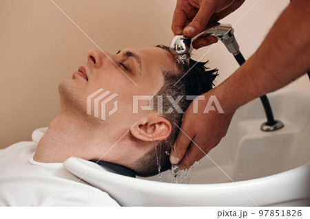Barber washing hair of caucasian man , close-up 97851826