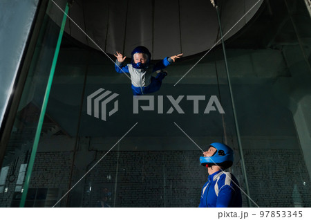 A man teaches a boy to fly in a wind tunnel. Lack of gravity. 97853345