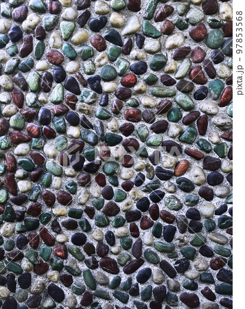 弱い日差しを受ける青緑色や茶色や黒色や白色の小石が埋め込まれた壁の縦長の背景画像 97853568