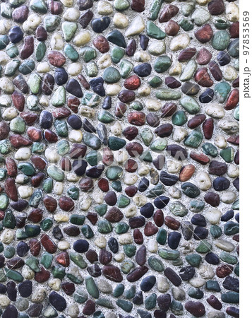 日差しを受ける青緑色や茶色や黒色や白色の小石が埋め込まれた壁の縦長の背景画像 97853569