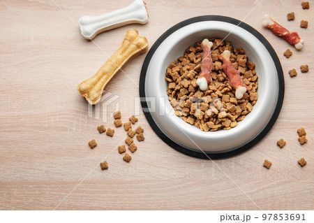 A bowl of dog food on a wooden floor. 97853691