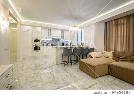 Open-concept studio apartment with classic kitchen in warm cream color and island for dining 97854196