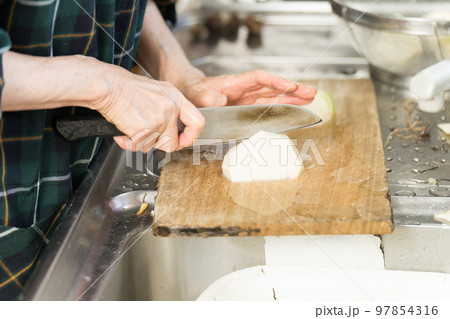 里芋の親芋を切るシニア女性 97854316