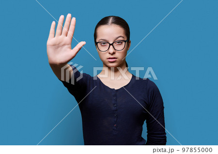 Serious confident teenage girl looking at camera making stop gesture with palm Serious confident teenage girl looking at camera making stop gesture with palm 97855000